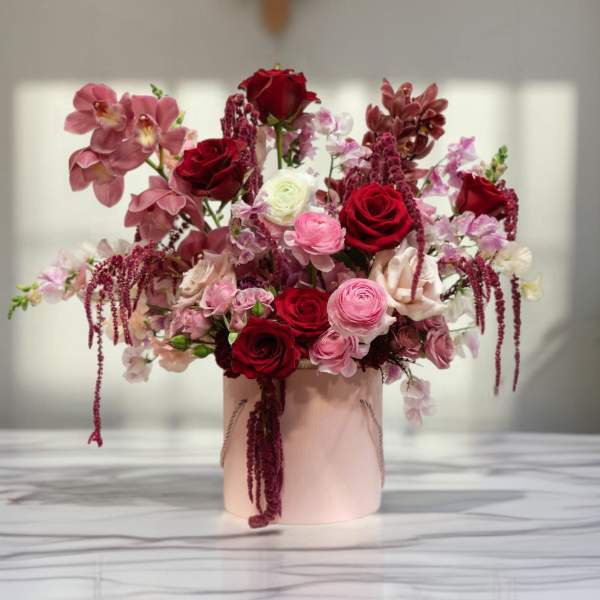 Pink and red floral arrangement in a blush vase