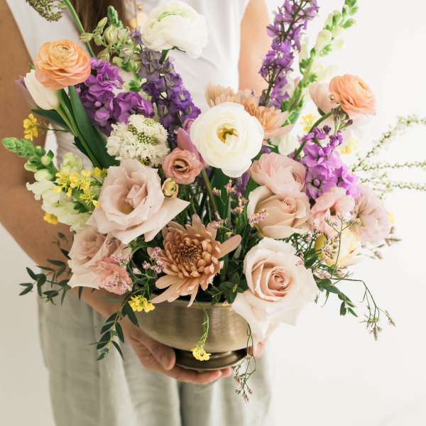 Mixed bouquet in a brass bowl with peach, white, and purple flowers