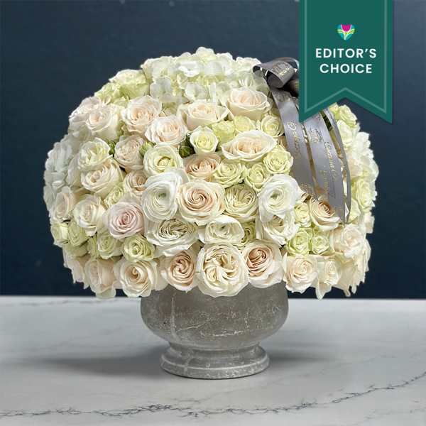 Cream rose bouquet in a gray urn vase with a ribbon bow