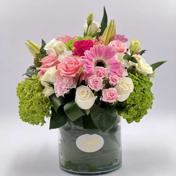 Pink and white roses with a pink gerbera daisy in a glass vase