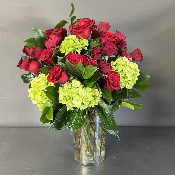 Bouquet of red roses and lime hydrangeas in a clear glass vase