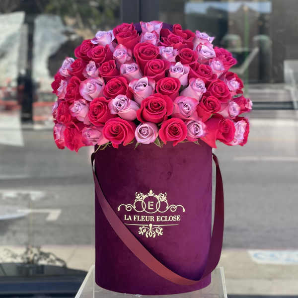 Bouquet of pink and lavender roses in a purple hatbox