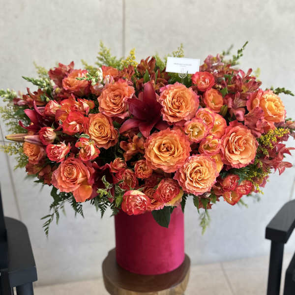 Large orange and pink floral arrangement in a magenta vase