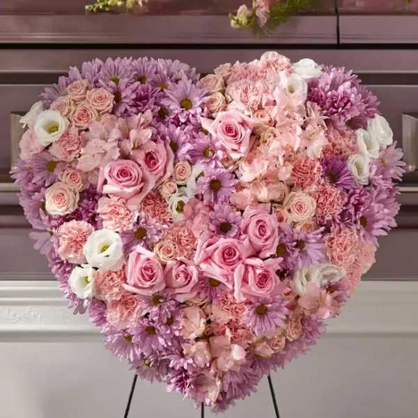 Heart-shaped floral arrangement of pink and lavender flowers on a stand