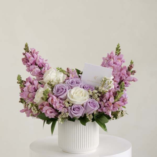 Pink and lavender roses arranged in a white ribbed vase