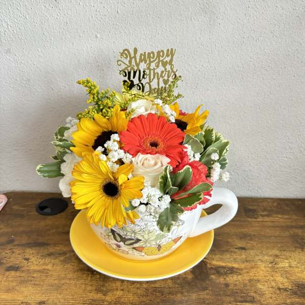 Flower arrangement in a teacup with a Mother's Day topper