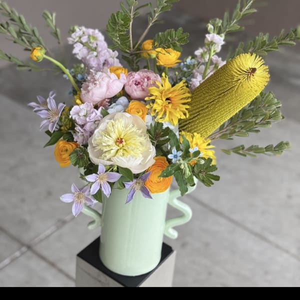 Mixed bouquet in a mint green vase with yellow, pink, and lavender flowers