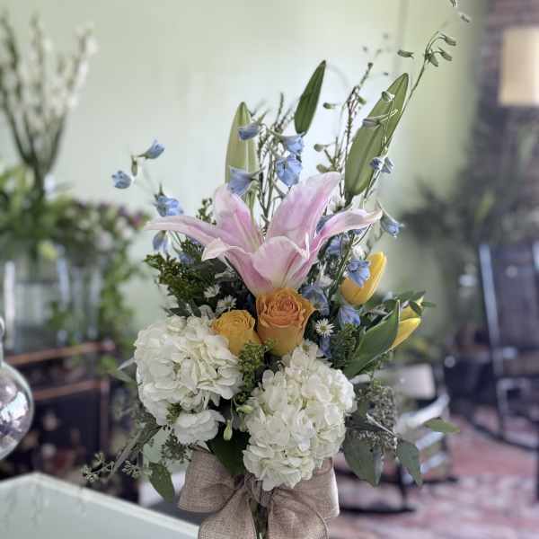 Bouquet of pink lilies, white hydrangeas, and yellow roses in a glass vase