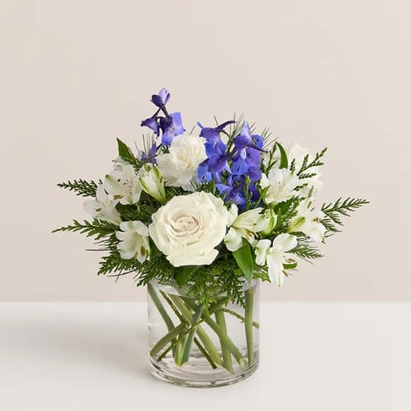 White and blue flowers arranged in a clear glass vase