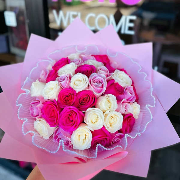 Bouquet of pink and white roses wrapped in pink paper