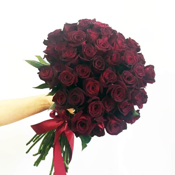 Handheld bouquet of deep red roses tied with a red ribbon