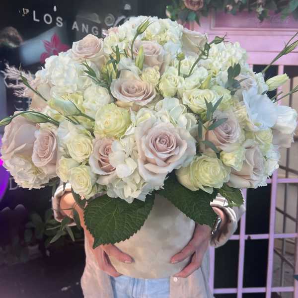 Large bouquet of pale roses and white hydrangeas in a cream vase