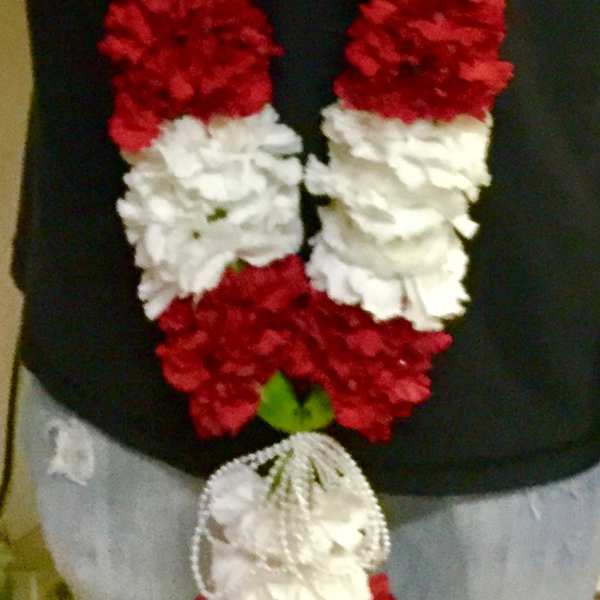 Person wearing red and white flower garlands around the neck