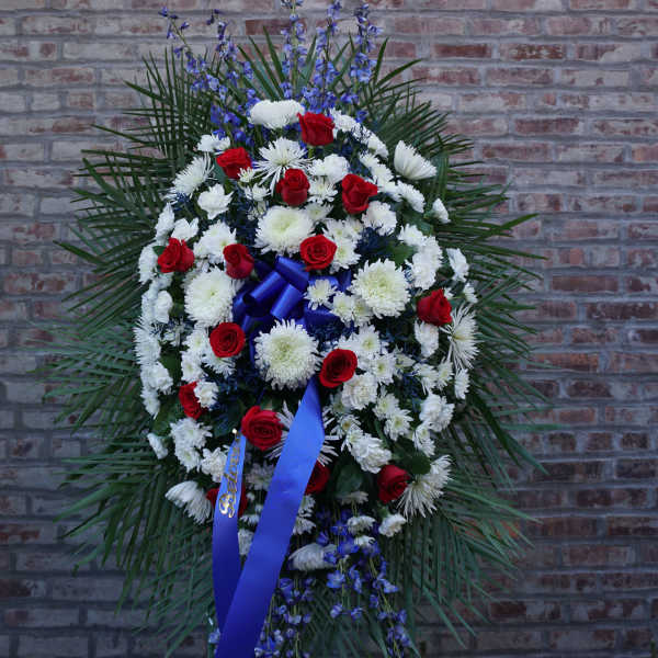 Standing funeral spray of red and white flowers with blue ribbon