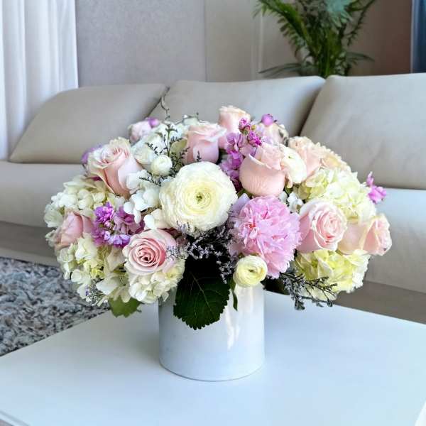 Pastel bouquet of roses, hydrangeas, and ranunculus in a white vase
