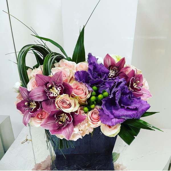 Pink roses and purple orchids in a dark square vase