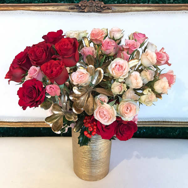 Bouquet of red and blush roses in a gold vase