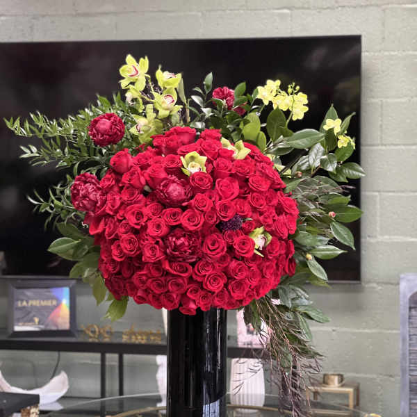 Large bouquet of red roses with yellow orchids in a black vase