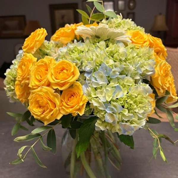 Yellow roses and pale hydrangeas in a glass vase