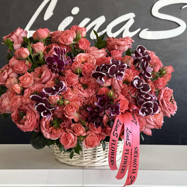 Pink rose bouquet with dark purple orchids in a white basket