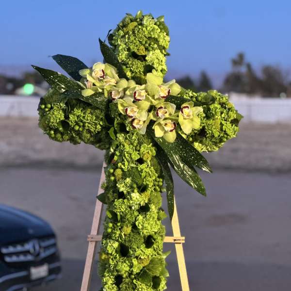 Green floral cross on an easel with pale orchids