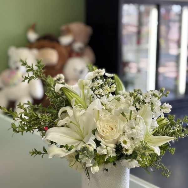 White lilies and roses arranged in a textured white vase