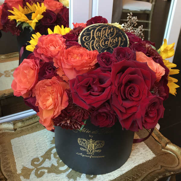 Bouquet of red, coral, and yellow flowers in a black hat box