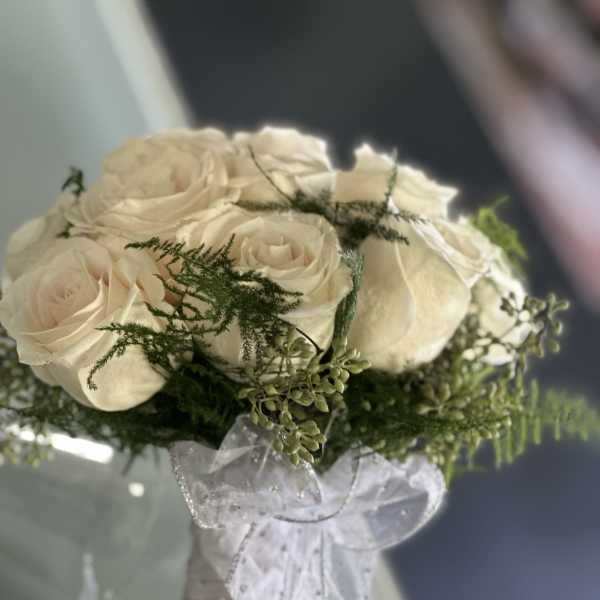 Bouquet of cream roses with greenery and a white ribbon wrap