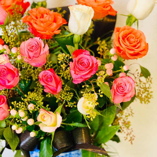 Bouquet of pink, orange, and white roses in a blue-and-white vase