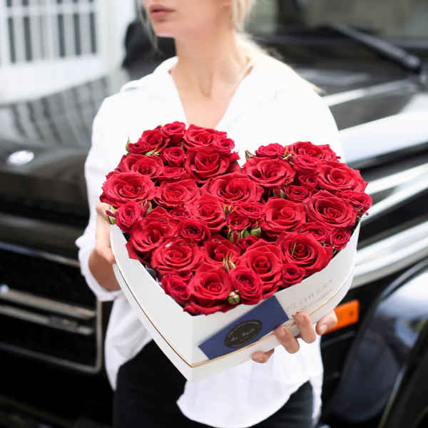 Heart-shaped box of red roses held by a person