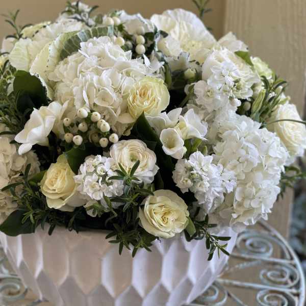 Low white and ivory flower arrangement in a textured white bowl