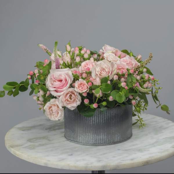 Pink roses and small blossoms in a gray ribbed container