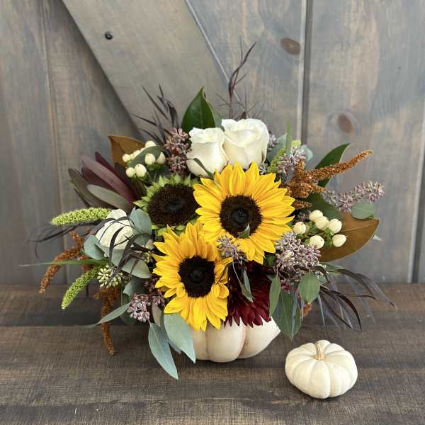 Sunflower and rose arrangement in a white pumpkin vase with a small white pumpkin beside it