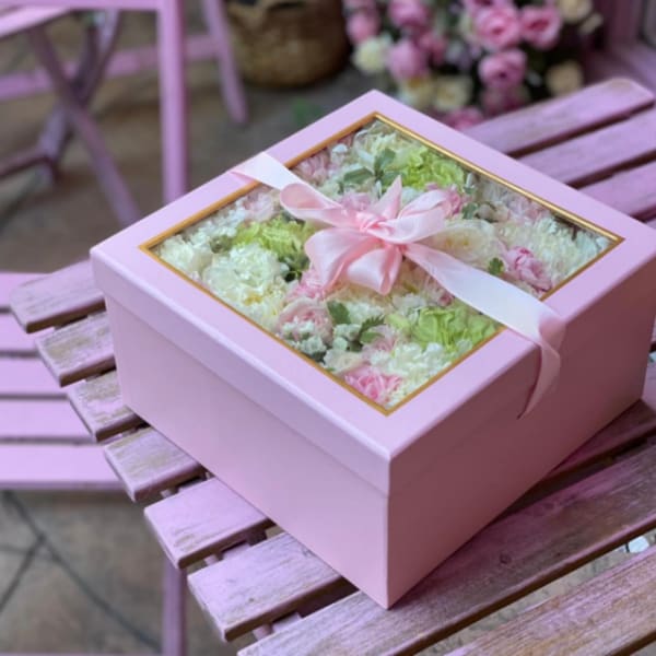Pink boxed arrangement of pastel flowers with ribbon and clear lid