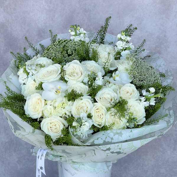 White rose bouquet with orchids in a white vase