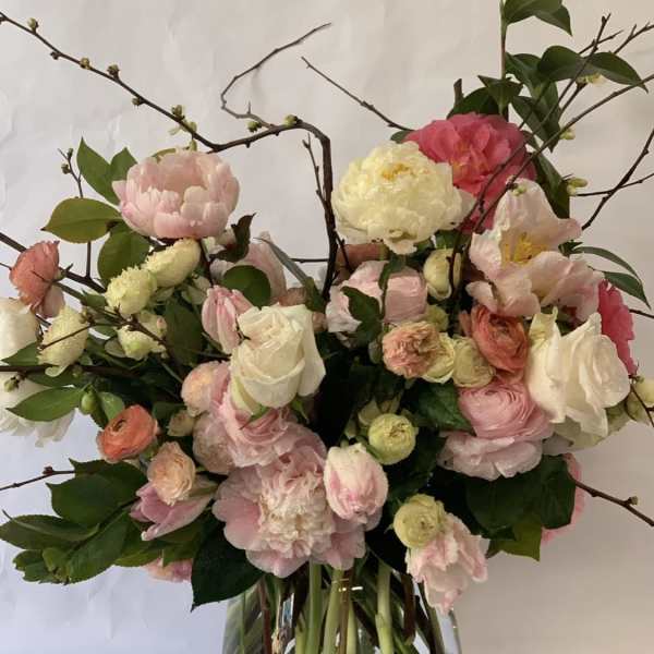 Pink and white flowers arranged in a clear glass vase with branching stems