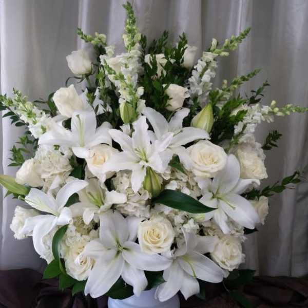 White lilies and roses arranged in a white vase