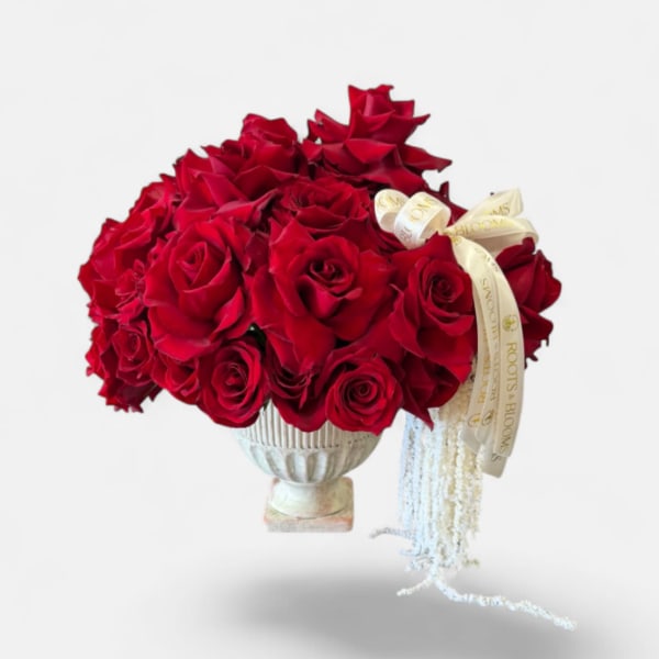 Bouquet of red roses in a silver vase with a cream ribbon