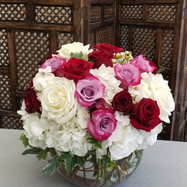 Bouquet of red, pink, and white roses in a glass bowl vase