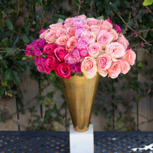 Pink and peach roses arranged in a gold vase