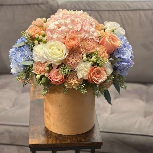 Pastel flower arrangement in a gold box on a wooden table