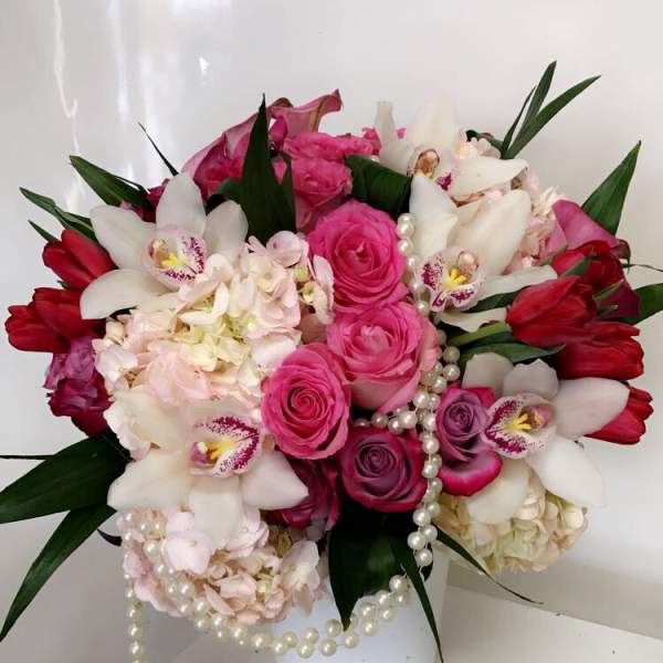 Pink and white floral arrangement in a white vase with pearl strands