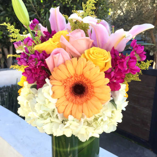 Colorful bouquet in a glass vase with lilies, roses, gerbera daisy, and hydrangeas
