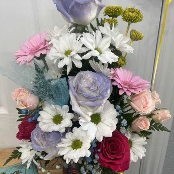 Mixed bouquet with lavender, pink, and white flowers in a decorative container