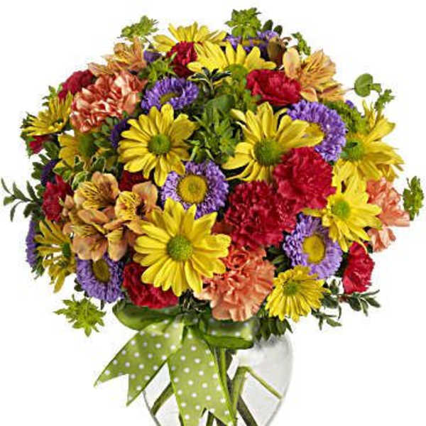 Colorful mixed bouquet in a clear glass vase with a green polka-dot ribbon
