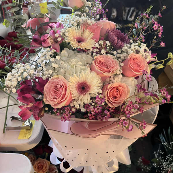 Pink and white mixed bouquet wrapped in pale paper with ribbon