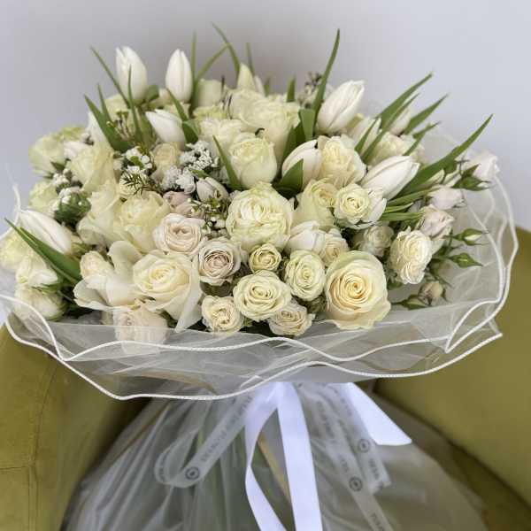 Cream rose and white tulip bouquet wrapped in sheer paper