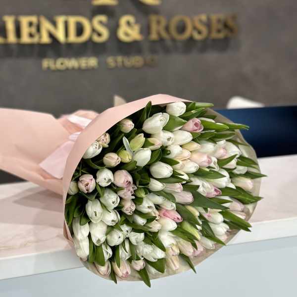 Bouquet of white and pale pink tulips wrapped in blush paper