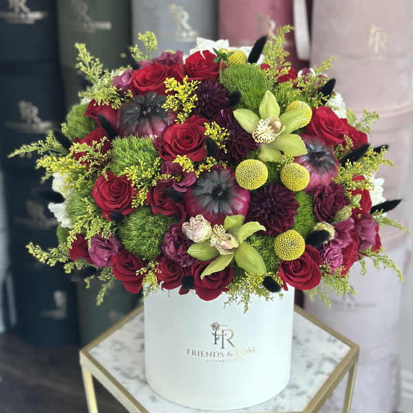 Round bouquet of red roses and green orchids in a white hat box