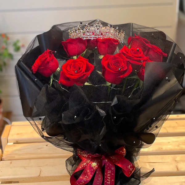 Bouquet of red roses wrapped in black mesh with a jeweled crown topper